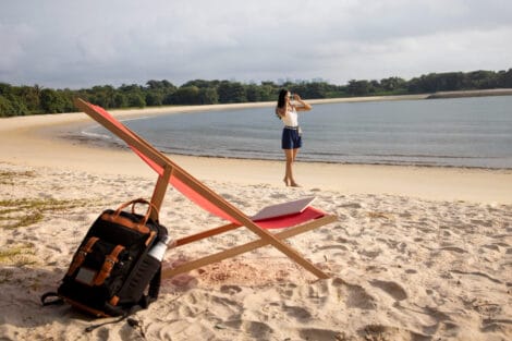 Digitaler Nomade mit Liegestuhl mit Laptop am Strand